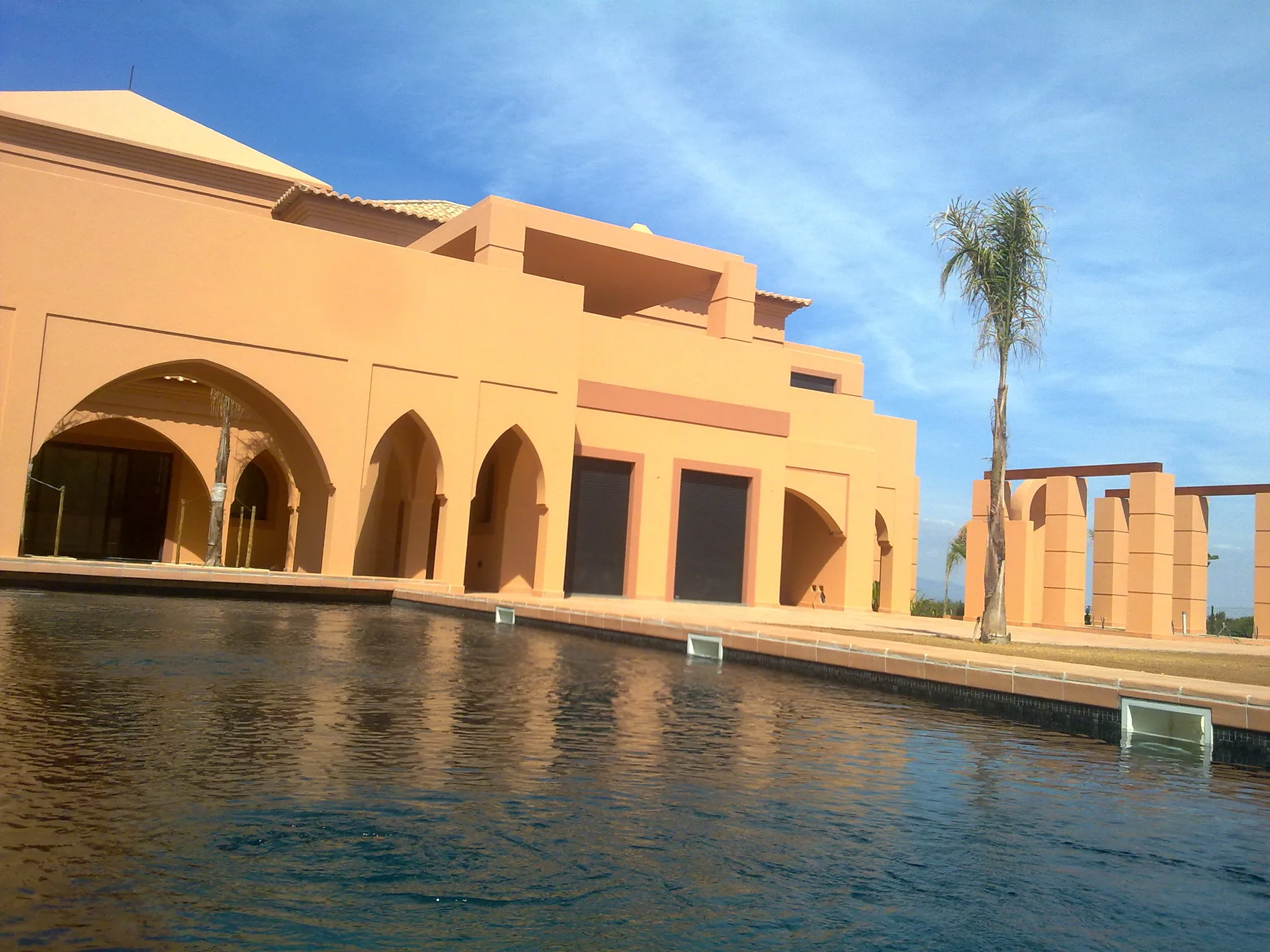 Arcos pontiagudos e terraço da Villa Kasbah refletidos na piscina