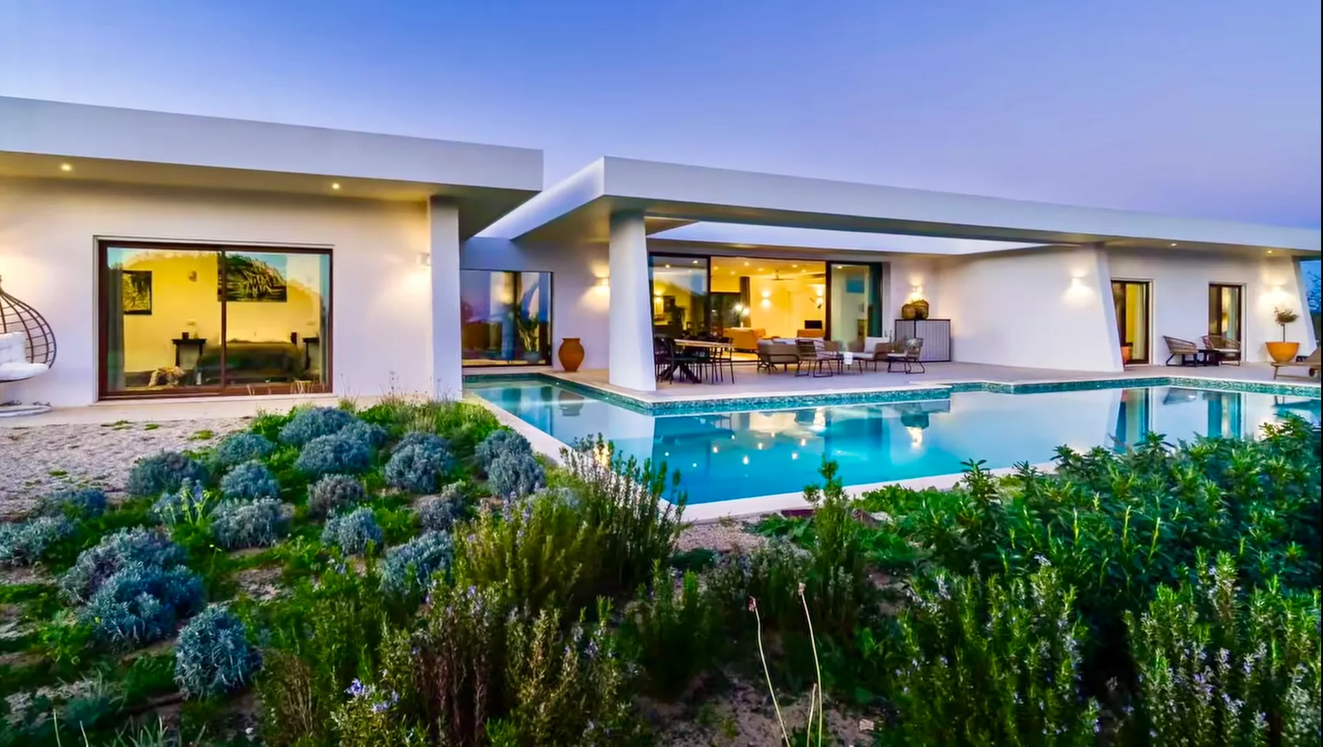 Piscina e terraço da Villa Porches vistos por entre arbustos floridos