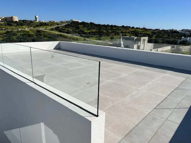 Terraço na cobertura com pavimento cerâmico e guardas de vidro em Porto de Mós