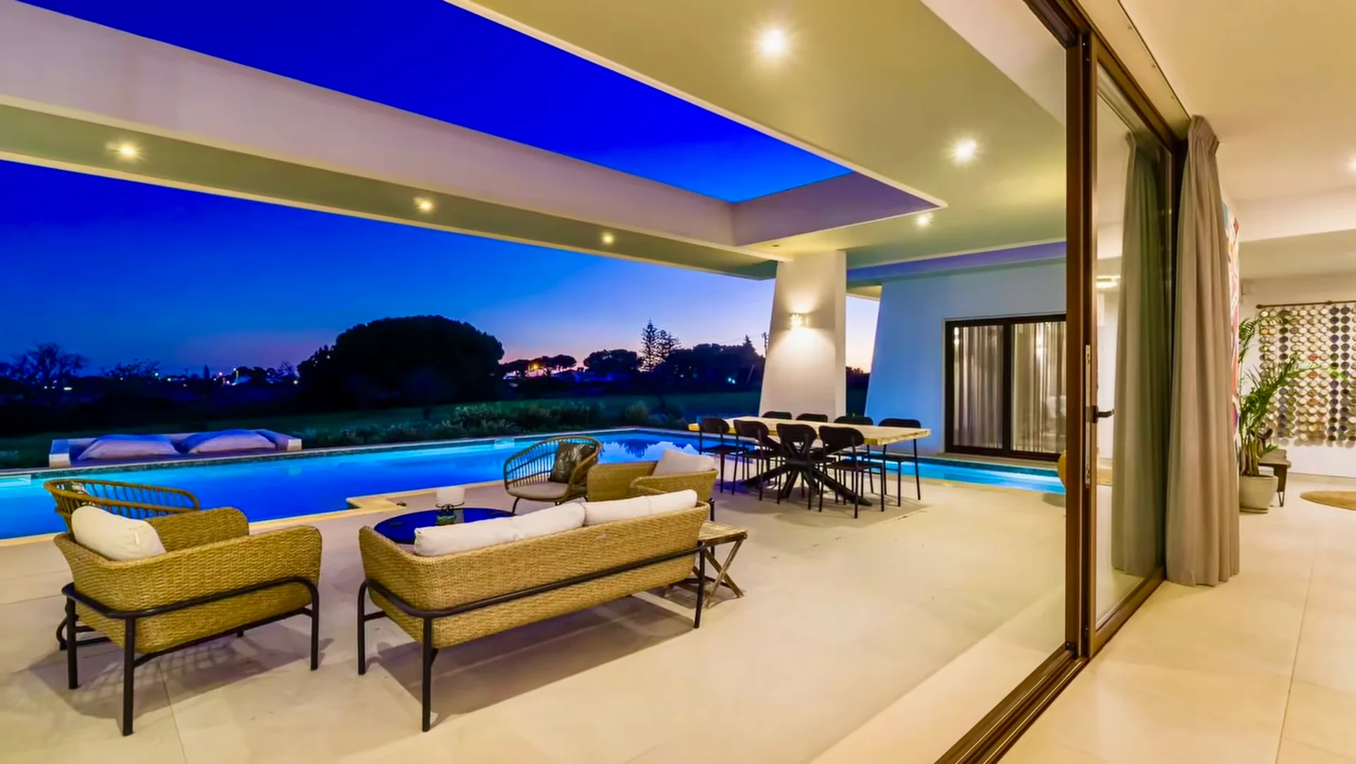 Espreguiçadeiras e terraço iluminado da Villa Porches ao anoitecer